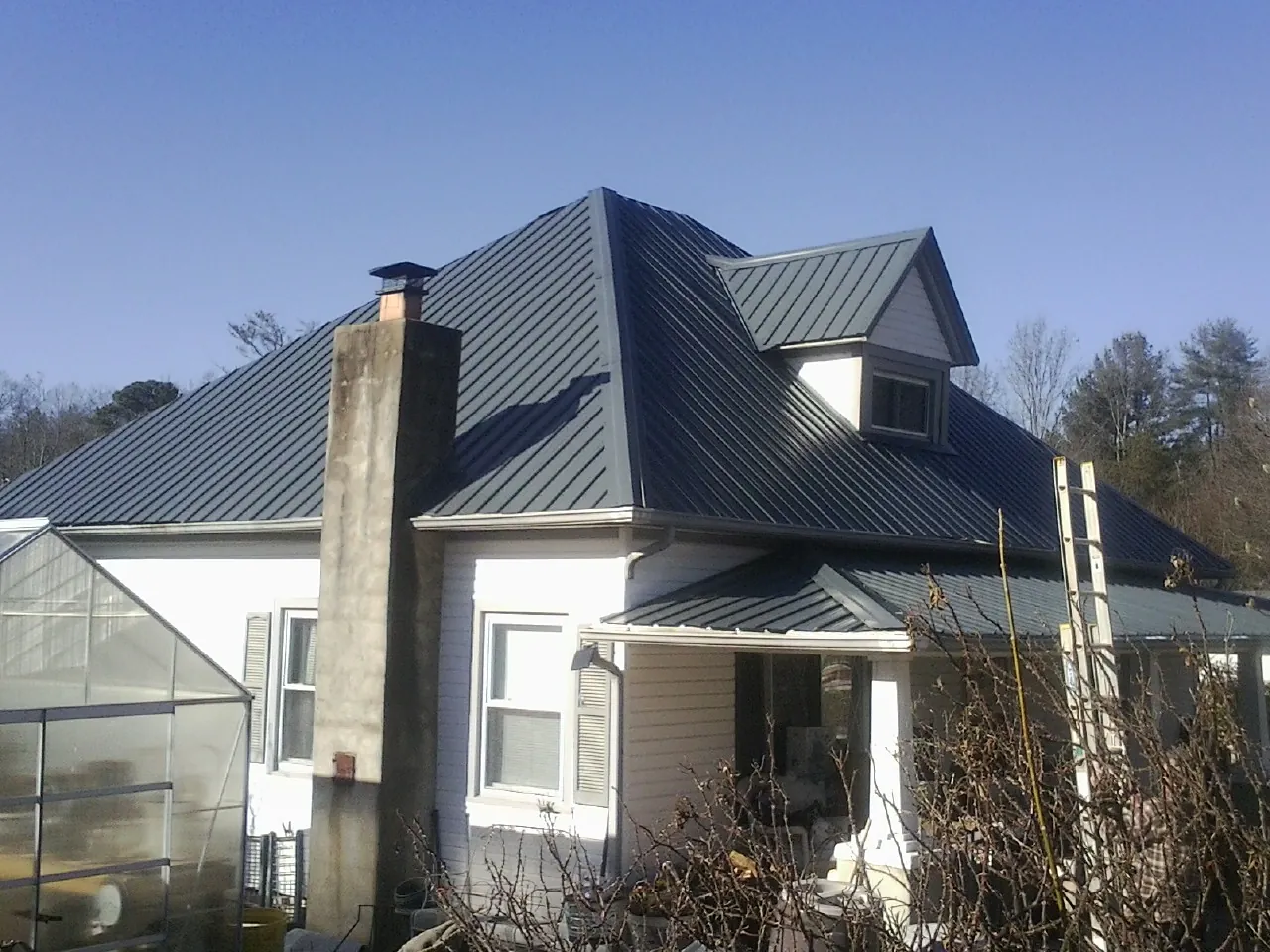 Dark blue standing seam metal roof on a white farmhouse with dormer — Slate & Tile Roof Repair by Roofing Brothers in Allamuchy