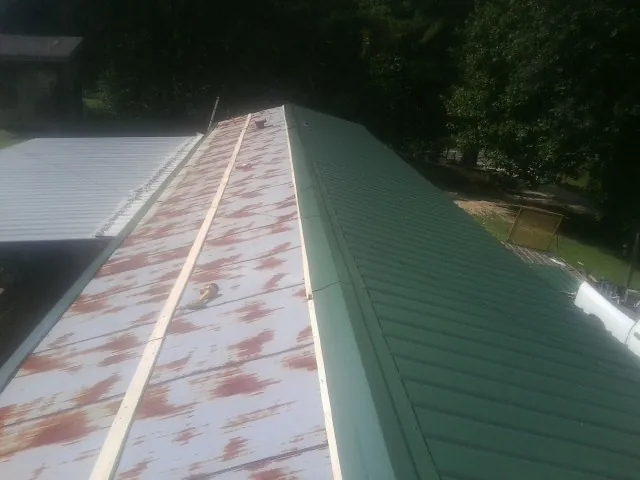 Old rusted panels beside newly installed green metal roofing — Wind Damage Roof Repair by Roofing Brothers in Allamuchy