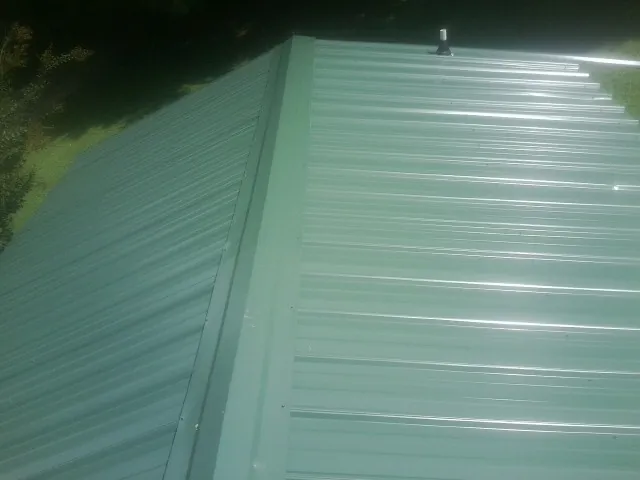 New green metal panels meeting at the ridge of a roof — Flat Roof Repair work by our crew in Allamuchy