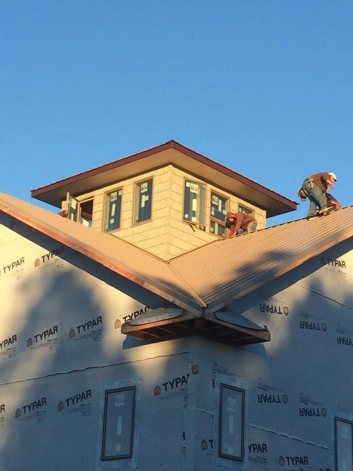 Roofers working around a rooftop cupola on a new metal roof at sunset — Roof Waterproofing in Allamuchy by Roofing Brothers